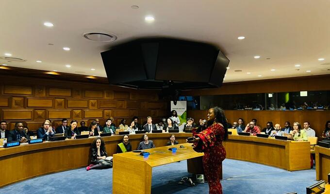 Woman speakers to a group of youth from around the world, in a UN conference room
