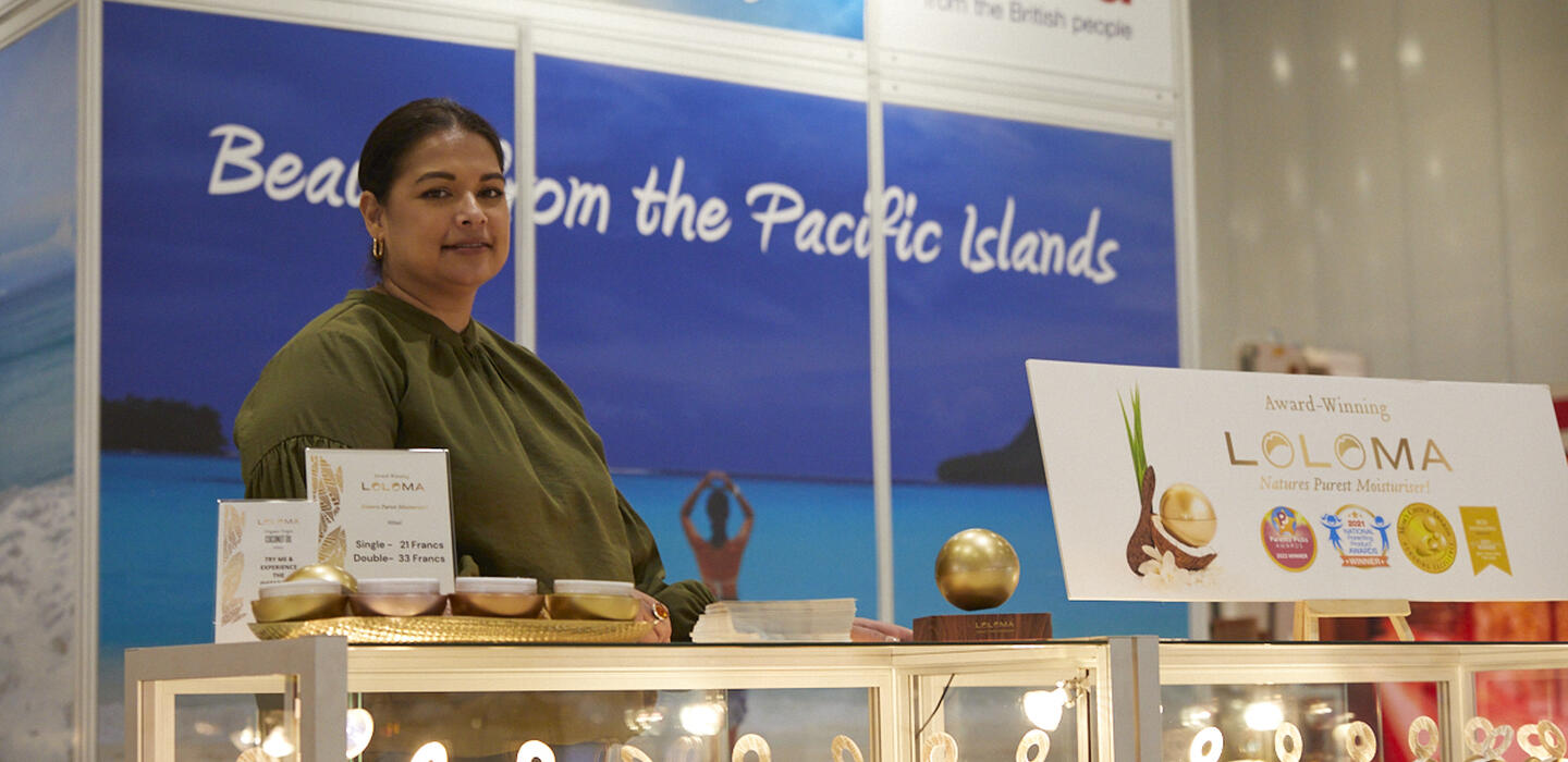 Woman from Fiji stands at counter at trade show for cosmetics