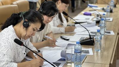 Uzbek women write on notepads in conference room