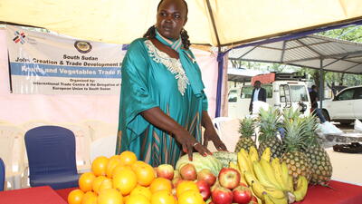 South Sudanese woman stands next to fruit stand