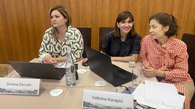 Three women in business attire sit at a table to hear a workshop on trade data