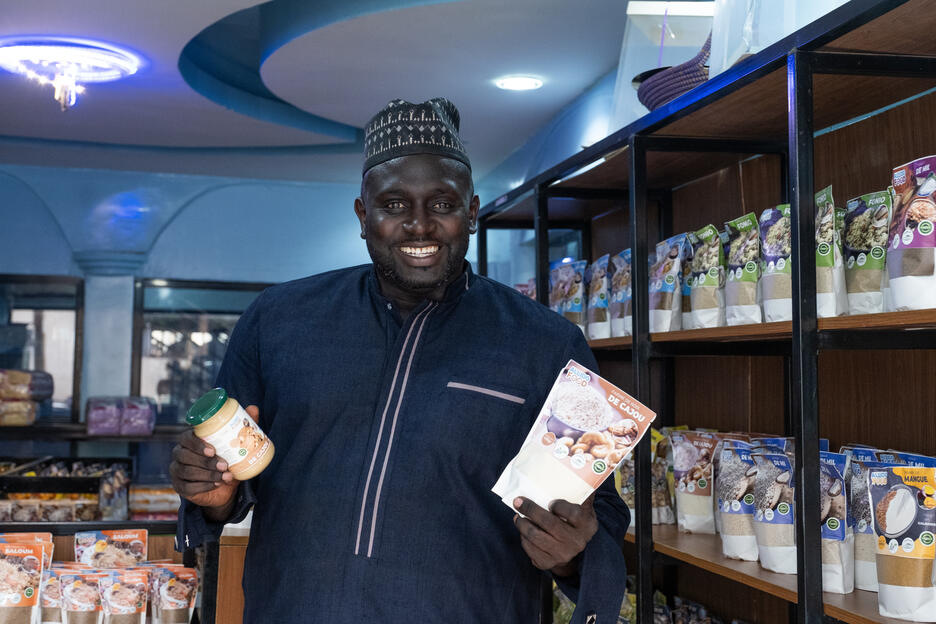 Hombre senegalés en una tienda sostiene en sus manos productos derivados del anacardo
