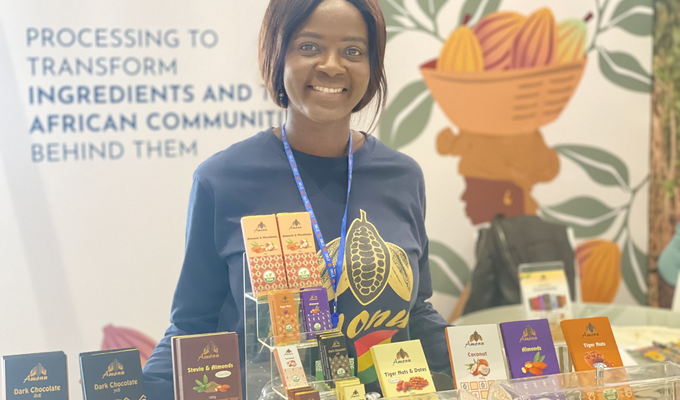 Ghanaian woman stands behind table of chocolate bars package in traditional motifs