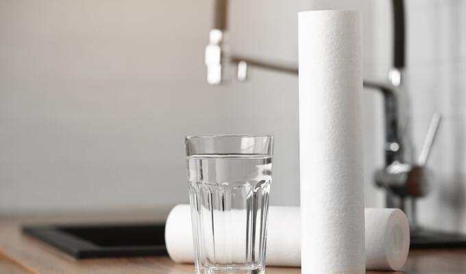 Clear glass of water on kitchen counter next to water filter
