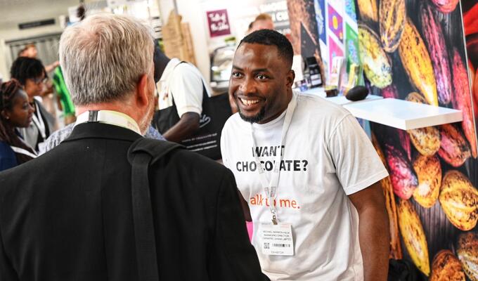Ghanaian businessman in white T-shirt speaks to customer at trade show