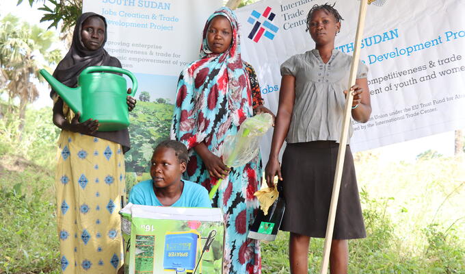 South Sudanese women hold box with new sprayer and water can
