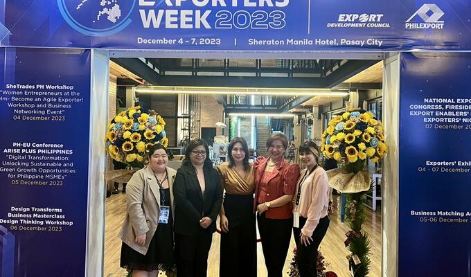 smiling Filipina women standing against National Exporters Week background 