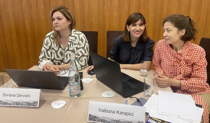 Three women in business attire sit at a table to hear a workshop on trade data