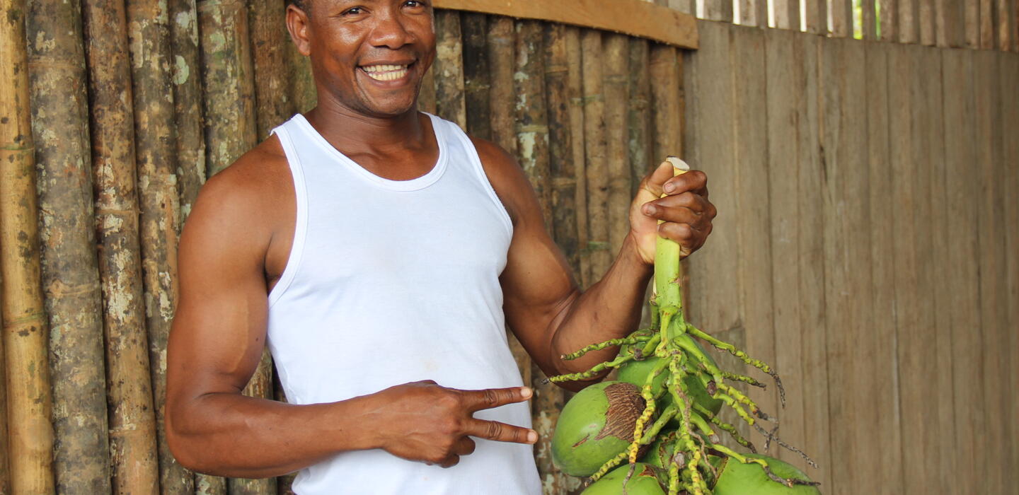 A man smiles and shows the bunch of fruits he holds in his hand