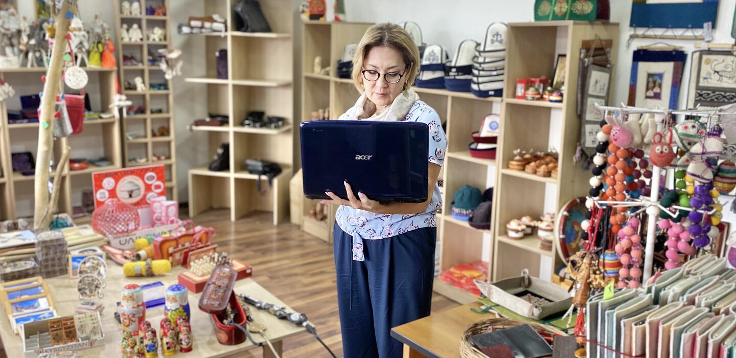 Woman holds laptop in handicraft store