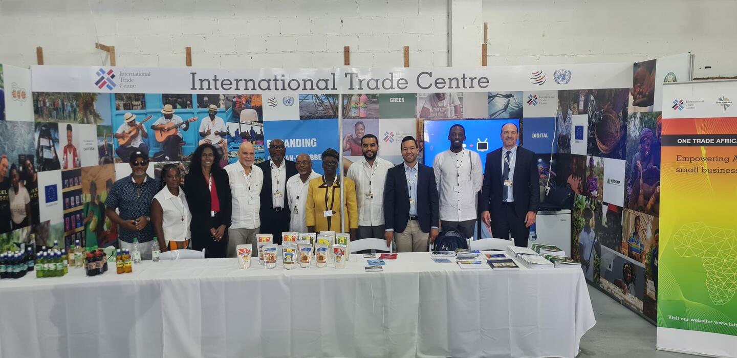 Group stands behind table, in front of signage for ITC programmes