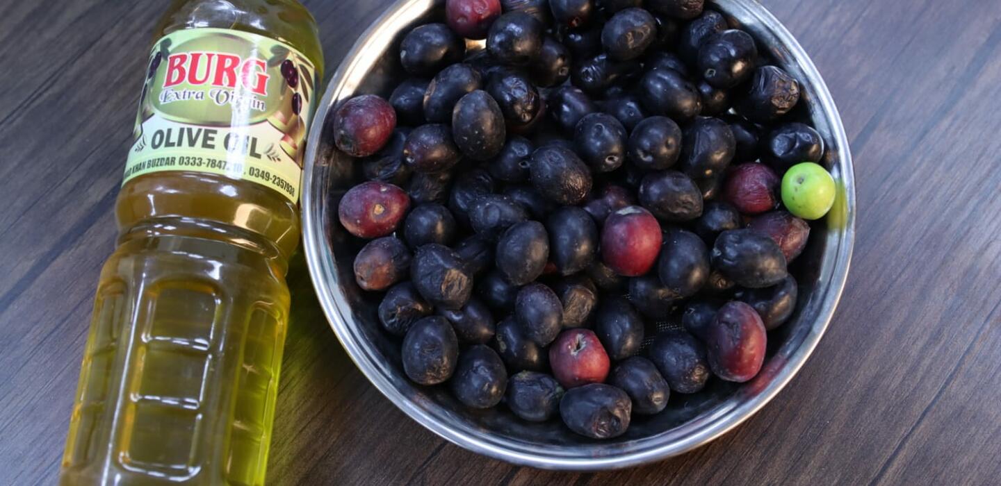 Bowl of black olives next to bottle of olive oil
