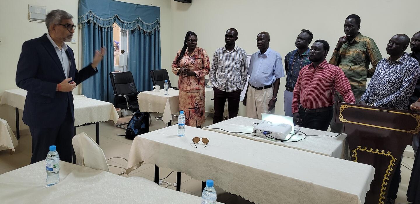 South Sudanese food safety advisors stand in a meeting room behind tables