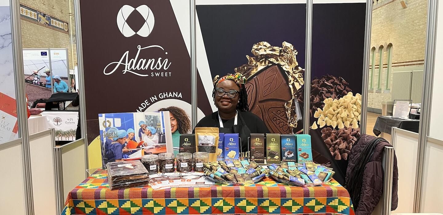 Una mujer ghanesa detrás de una mesa de tabletas de chocolate en una feria comercial.
