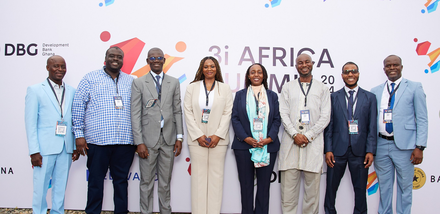 Eight West African business people stand on red staircase below a banner, reading in part “3i Africa Summit”