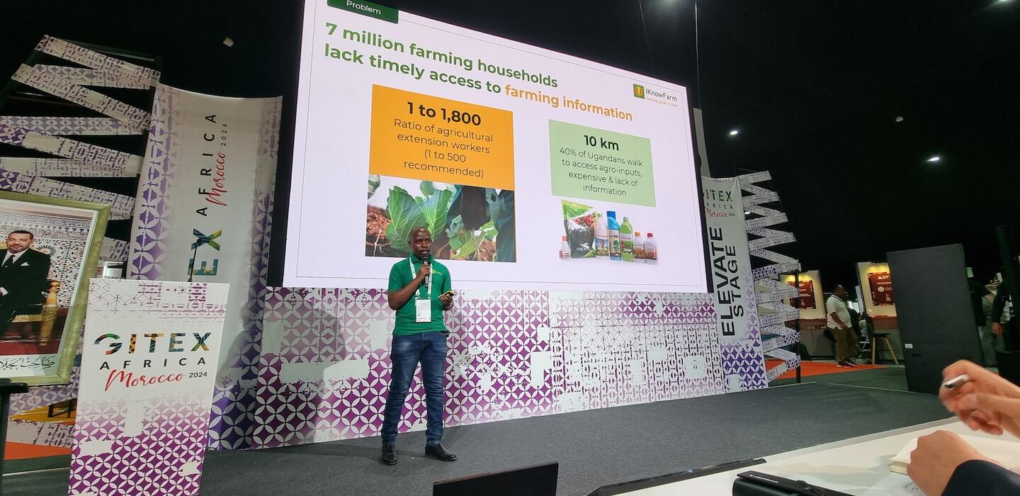 Uganda tech entrepreneur in green shirt speaks from stage with GITEX signage