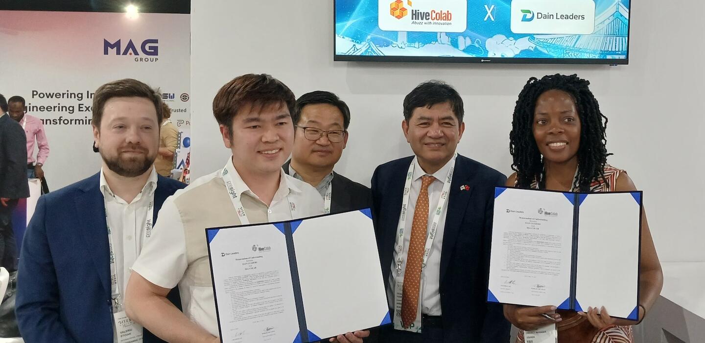 Korean and Ugandan tech business leaders hold documents for camera