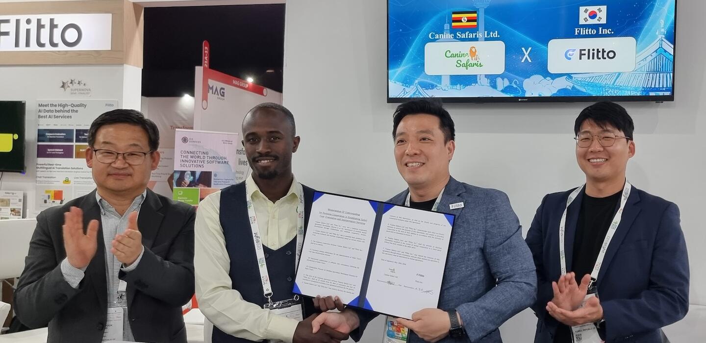 Korean and Ugandan tech entrepreneurs hold documents for camera