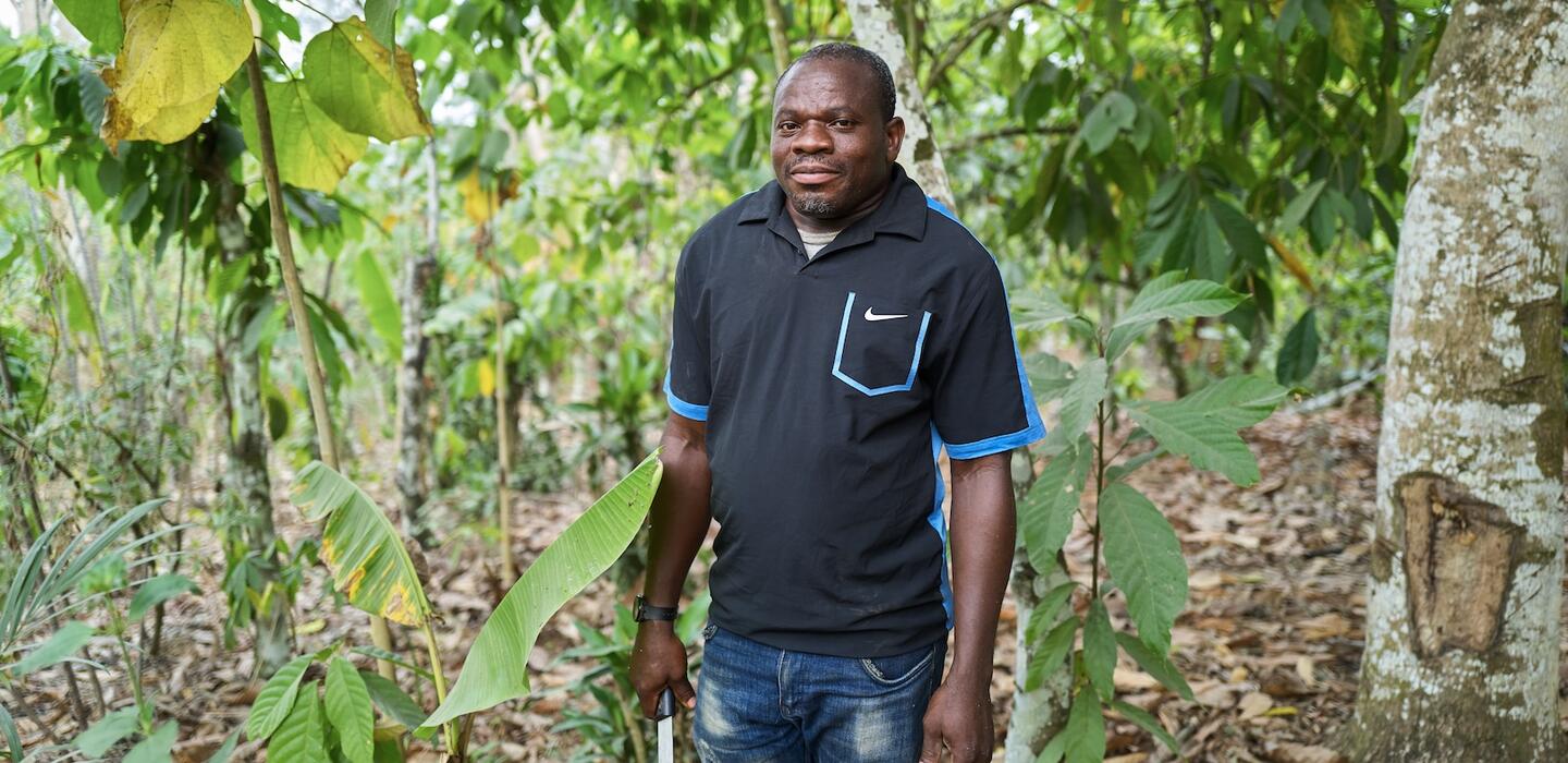 Ghanaian farmer stands in forest 