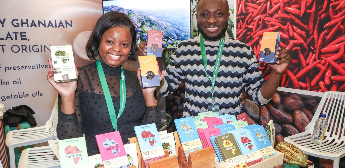 Ghanaian man and woman hold brightly coloured packets of chocolate