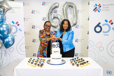 Dos mujeres sonriendo y posando frente a un pastel bellamente decorado en un evento de celebración.