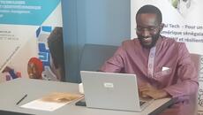 Man sits behind laptop in front of banner for the ITC NTFV Senegal Tech project